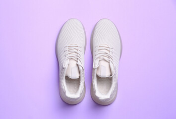Stylish sporty sneakers on light violet background, top view
