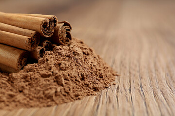 Cinnamon powder and sticks on wooden table, closeup. Space for text