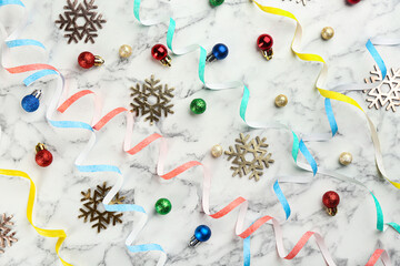 Flat lay composition with serpentine streamers and Christmas decor on white marble background
