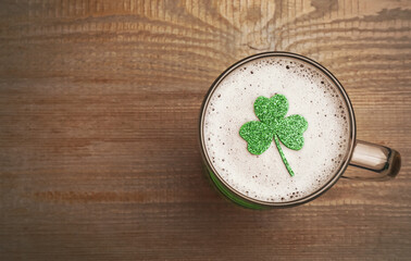 Top view of beer with clover leaf on wooden table, space for text. St Patrick's Day celebration