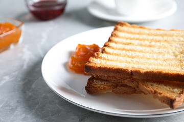 Tasty toasts and jam served on grey marble table, closeup. Space for text