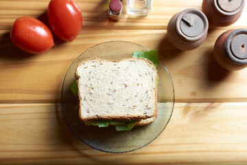 A top view of vegan sandwich surrounded by tomatoes, spices and condiments. View of bread slice with poppy, sunflower and flax seeds, and oat.