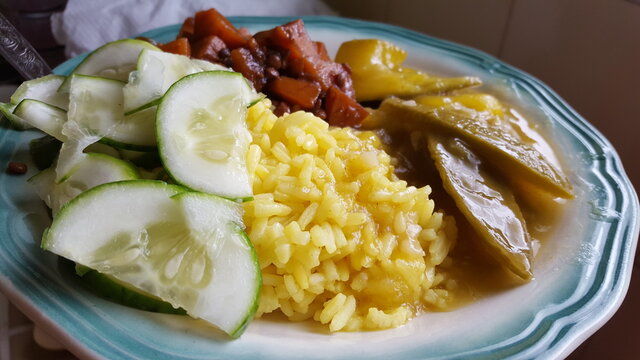 A delicious plate of home-cooked rice, potatoes, beans, and curried mangoes with slices of cucumbers is a perfect food photography shot. Portraying Indigenous cuisine.  