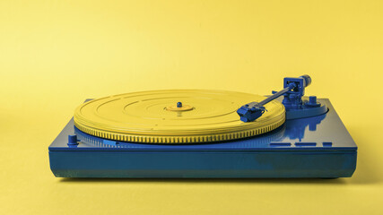 Blue and yellow vintage vinyl record player on a yellow background.