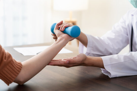 The doctor performed hand physical therapy for the patient with dumbbells.