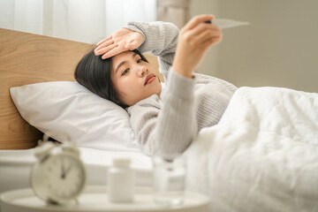 young women sick sleep put hands on forehead with look up to digital thermometer, healthcare concept.