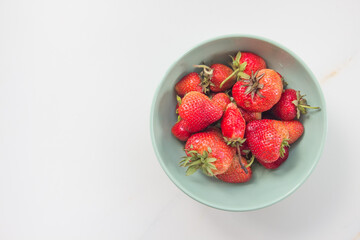 Early pesticide grown strawberries. Hard and not sweet strawberries, not grown correctly. Strawberries in a bowl with text spaces