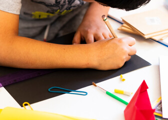 Child drawing on a black sheet. Playful activities at home concept.
