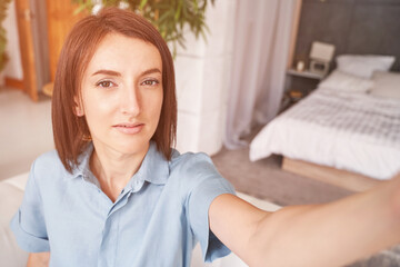 Young woman doing self portrait inside home. Blogger selfie video. Happy emotion. Smiling female person. Lifestyle action. Pretty posing