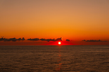 フェリーから眺める水平線に沈む赤く燃える夕日