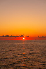 フェリーから眺める水平線に沈む赤く燃える夕日