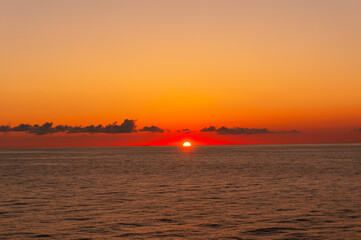 フェリーから眺める水平線に沈む赤く燃える夕日