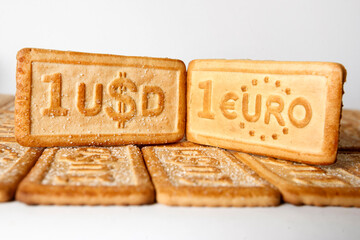 Two cookies with the one euro and one dollar currency symbols on the white background.