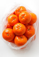 Ripe tangerine citrus fruit in a plastic bag on white background