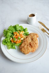 a plate of crispy chicken steak and vegetables with black pepper sauce in white background 
