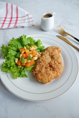 a plate of crispy chicken steak and vegetables with black pepper sauce in white background 