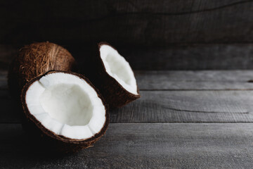 Broken coconuts on gray wooden background. White coconut pulp