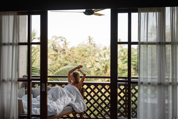 Home lifestyle woman relaxing sleeping on sofa on outdoor balcony with tropical view, lie under...