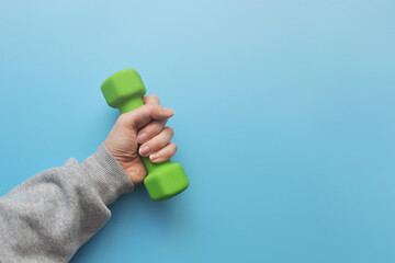 Green dumbbells in the hands of a man. Sports and healthy lifestyle in the modern world