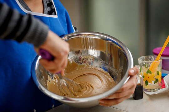 Mujer mezclando ingredientes en recipiente para preparar un panque de pl&aacute;tano. concepto de reposter&iacute;a en casa