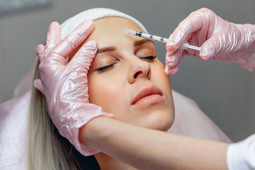 Cosmetologist performing Botox injections to rejuvenate the frontal part of the face. Cosmetic...