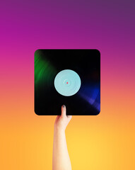 A hand holds a square vinyl music record on a yellow-pink gradient background
