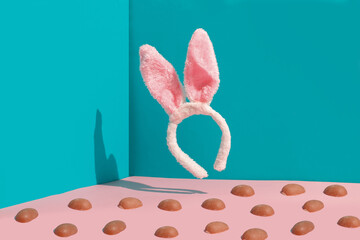 Modern Easter composition. In the frame there are bunny ears and pieces of chocolate eggs on a blue-pastel background.