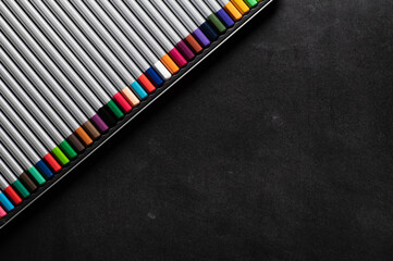 a set of colored pencils for pastels on a black magnetic board for notes on the refrigerator