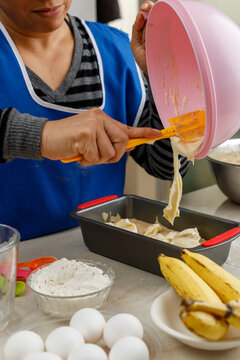 Reposter&iacute;a en casa. Mujer mexicana preparando un panque de pl&aacute;tano, vaciando la masa en el recipiente para meterlo al horno.