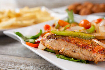 A closeup view of a grilled salmon steak, in a restaurant or kitchen setting.