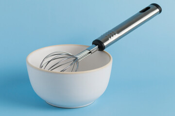 bowl and whisk on blue background. Kitchenware.