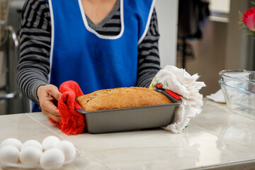 Repostería en casa. Mujer sacando del horno un Panque recién horneado.