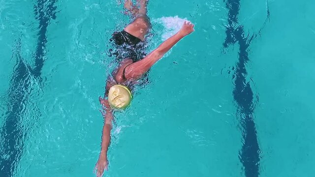 Overhead tracking shot of an athletic woman swimming in a pool 