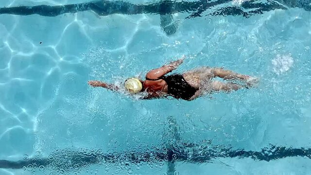 Athletic woman swimming freestyle in a pool - overhead tracking view in slow motion