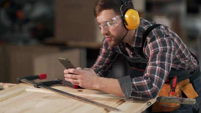 handsome man in work uniform takes pictures on the phone wooden products