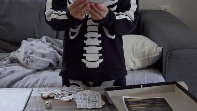 Happy caucasian boy, counting classic game Monopoly fake money at home