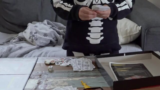 Close up on caucasian boy, counting fake monopoly money, tilt down shot