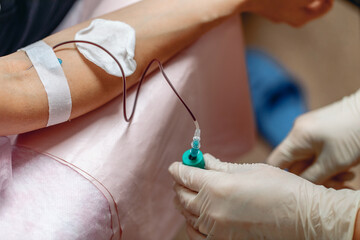 Gentle hands of a nurse taking blood from a patient's vein. Close-up. Gloves on the hands of a...