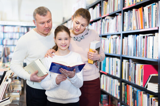 Portrait of happy mother and father with daughter browsing books in library