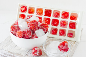 Frozen strawberry with crystals of ice on pink background