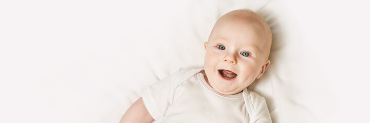 Cute small boy lying at bed. Childhood concept. Light background. Smiling child. Happy emotion....