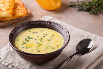 Cheese soup with yellow sweet pepper and thyme on a beige background. Vegetarian food.