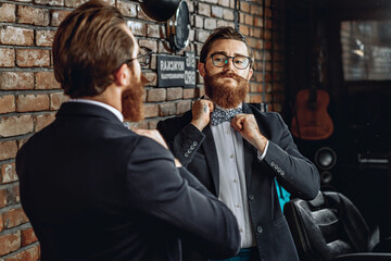 Portrait of an adorable stylish man with glasses, beard and mustache, looking at himself in the...