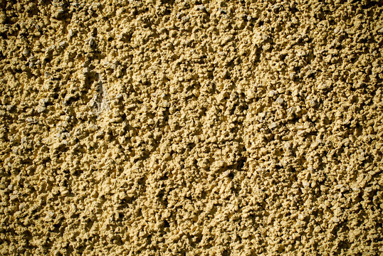 Rough wall texture under the strong sun light. Yellow wall background.