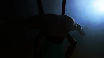 Aerial yoga woman practicing inverted butterfly pose hanging upside down using hammock enjoying healthy fitness lifestyle exercising in studio training