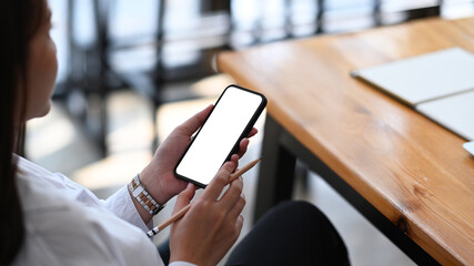 Close up view of young woman entrepreneur using mobile phone at her workplace.