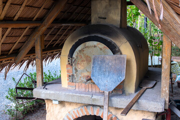 Traditional oven with baking tools. Pizza and bread cooking in wooden oven. Ceramic masonry oven in vintage style