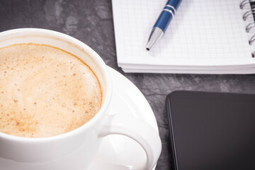 Smartphone, coffee with milk and notepad for notes. Work or relaxation with mobile phone