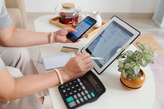 Hands of senior woman checking investment account via application on tablet computer and buying new stocks and receiving dividends