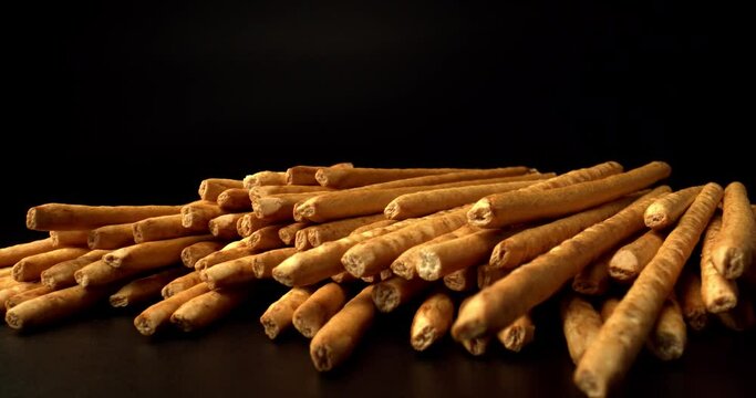 Mound of Sweet sticks on black table, close up. Bread Straw. Pretzel Sticks. Snacks production conveyor, baked ready. High quality. 